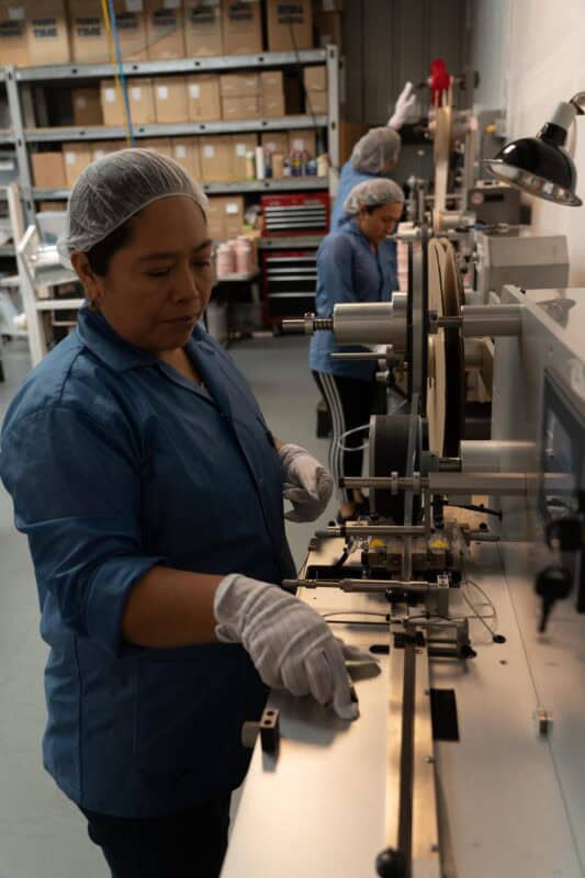 Workers on SMT production line handling Leader Tape Extenders and SMD components