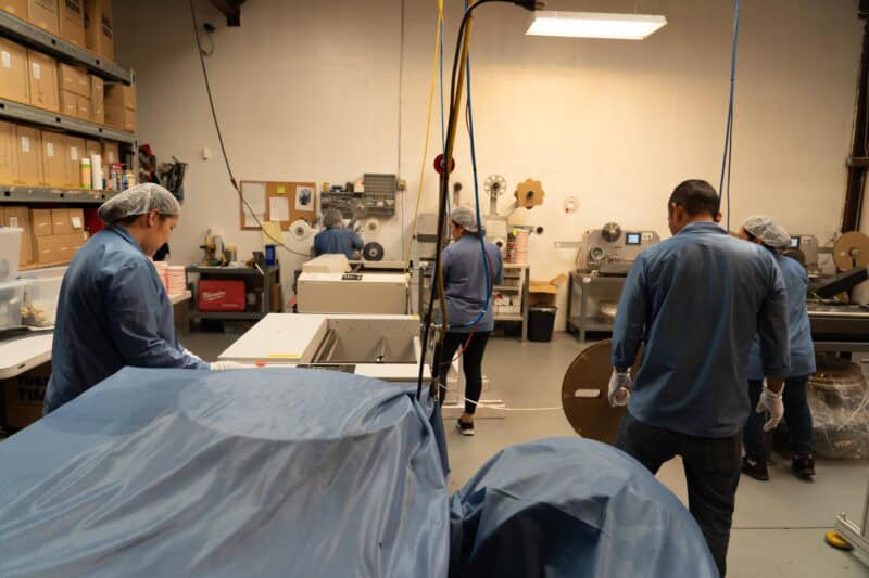 Workers on SMT production line handling Leader Tape Extenders and SMD components