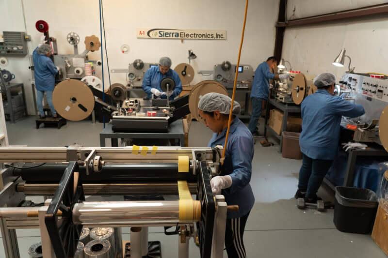 Workers on SMT production line handling Leader Tape Extenders and SMD components