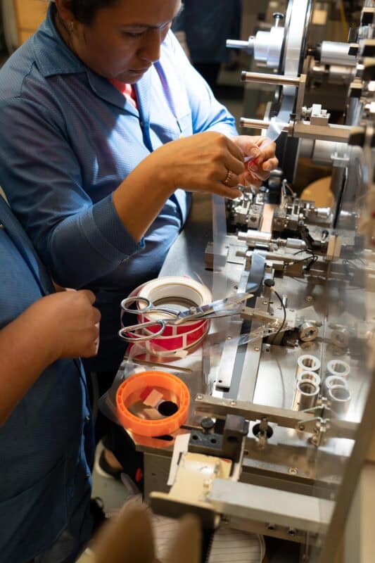 Workers on SMT production line handling Leader Tape Extenders and SMD components